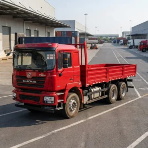 Shacman F3000 6x4 cargo truck, 10 wheels, red cab and 8.6 m drop-side cargo body, in a logistics yard