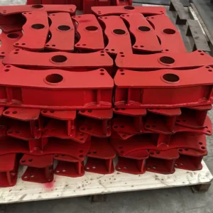 Red semi-trailer suspension equalizers (balance beams) stacked on a pallet in the workshop